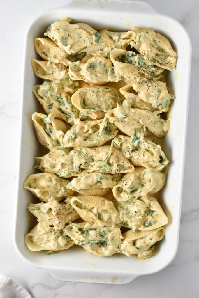 Unbaked butternut squash stuffed shells in a white baking dish