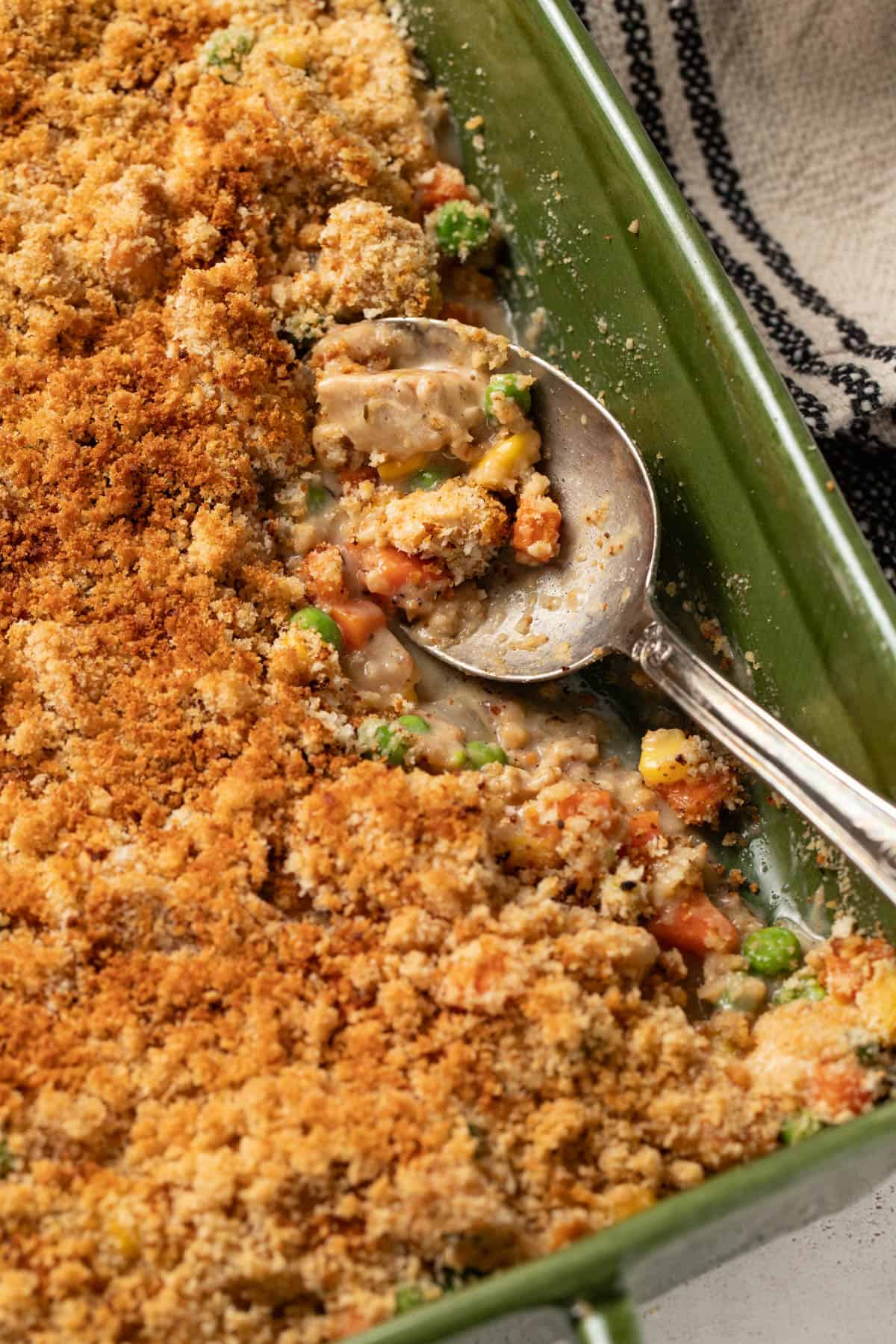A spoon scooping up the chicken pot pie filling topped with crunchy panko.