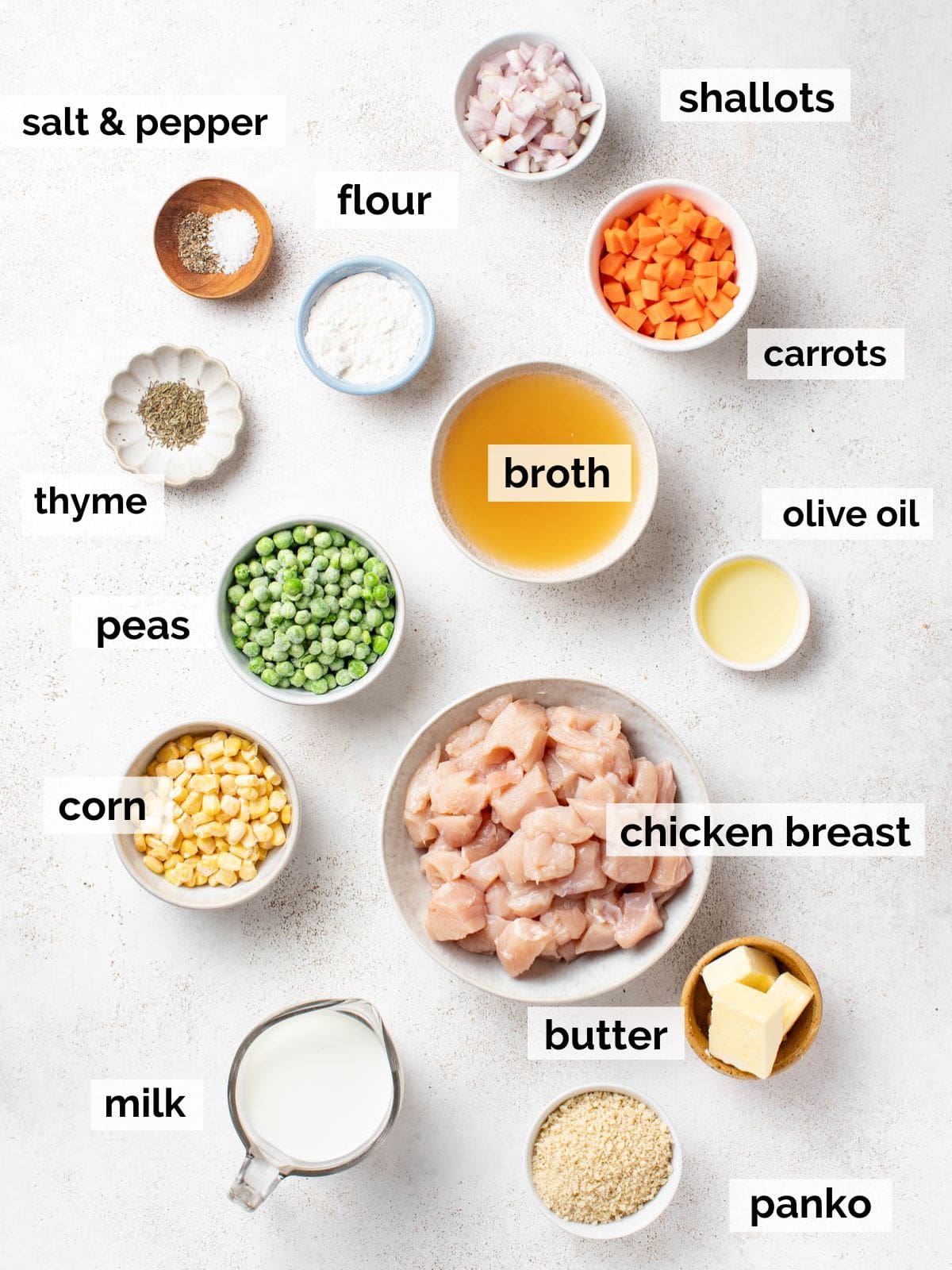 Ingredients for chicken pot pie without the crust like chicken, vegetables, and broth on a white background.