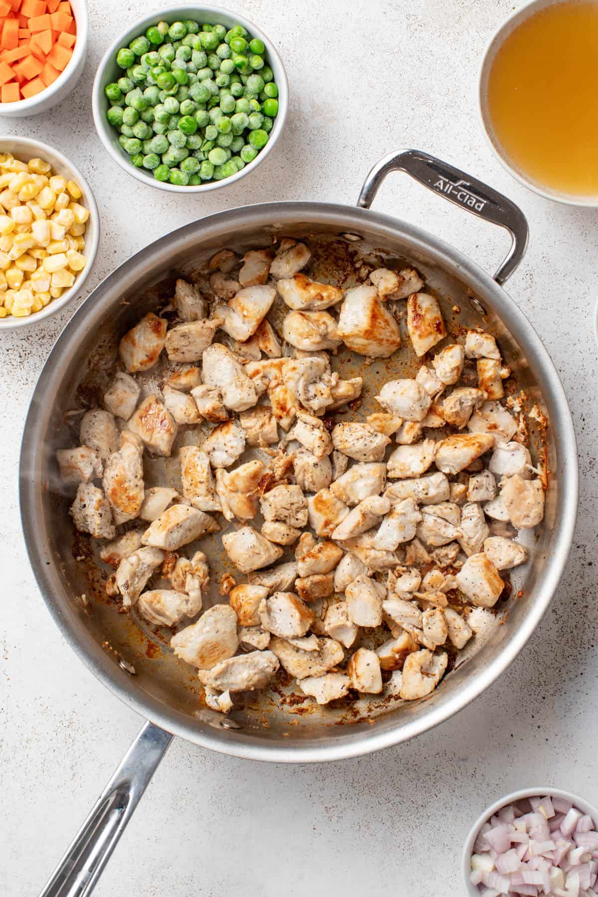 Browning chicken breast in a stainless steel pan.