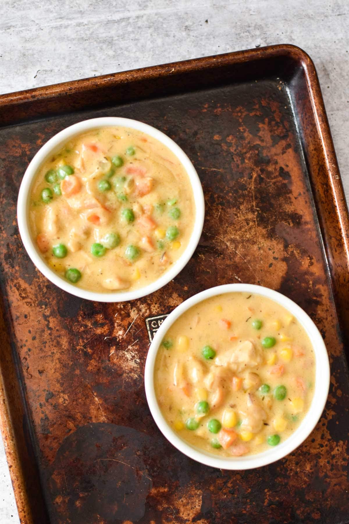 Two chicken pot pies without the crust on a baking sheet