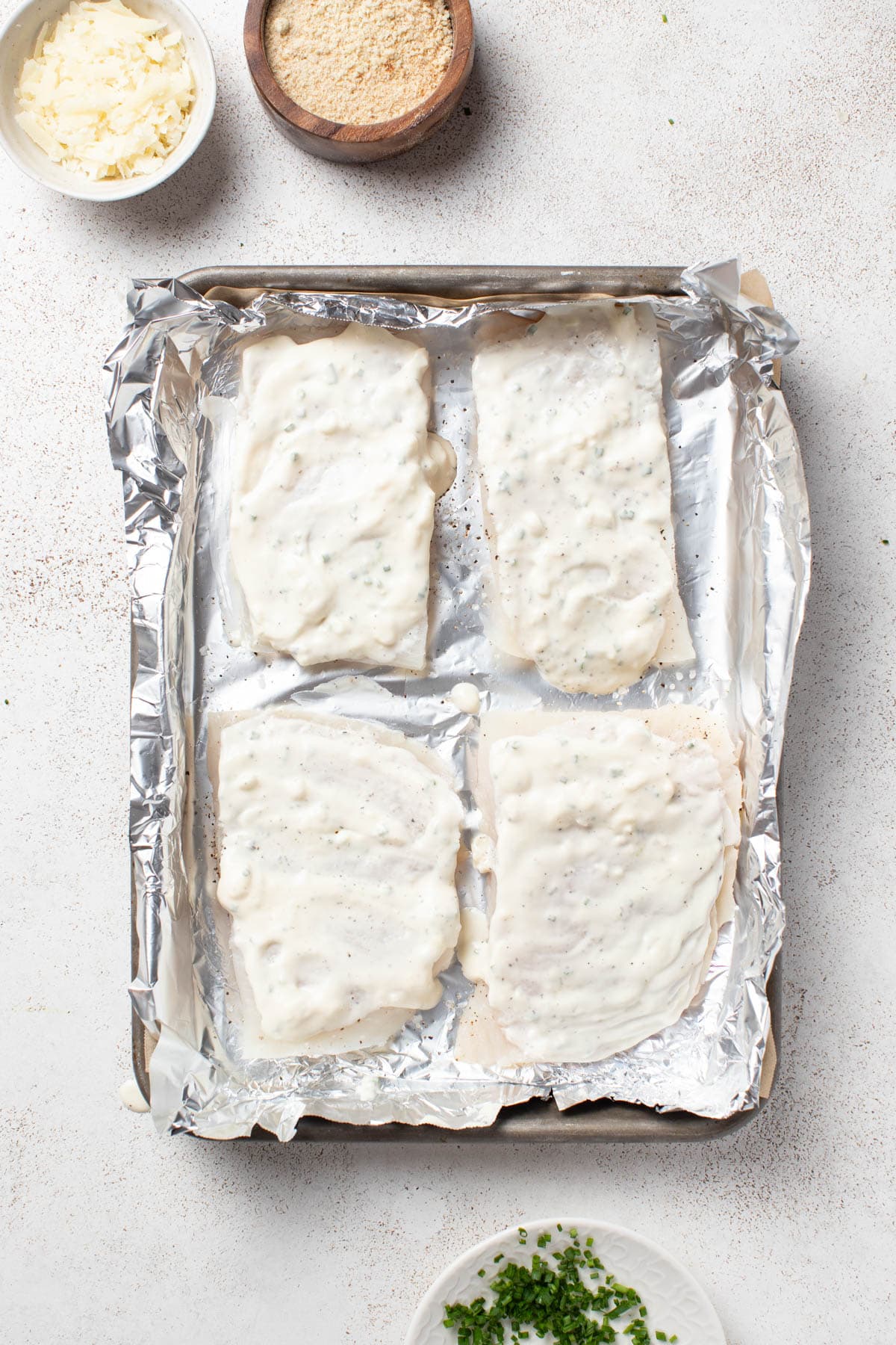 Spreading mayo on top of the halibut fillets. 