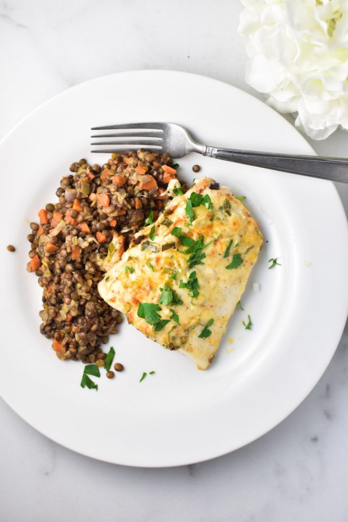 Heavenly halibut on a white plate with french lentils and a fork