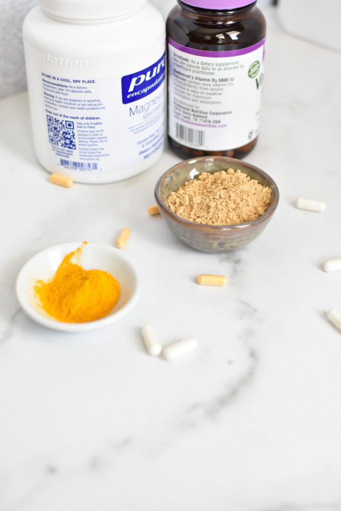 Migraine supplements like magnesium, ginger, and vitamin d on a white marble table