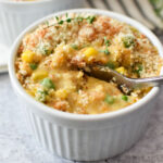 A spoon dipping into a white ramekin with crustless chicken pot pie.