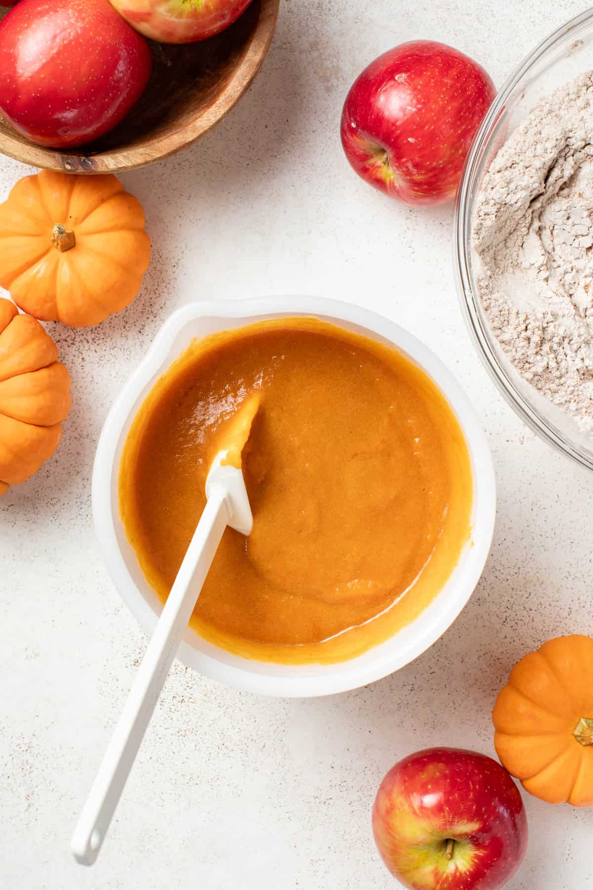 Mixing eggs and sugar with pumpkin and oil in a bowl.