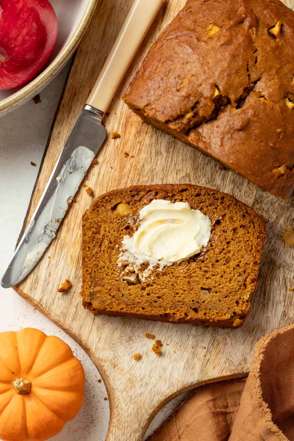 A slice of apple pumpkin bread with butter smeared on top of it.