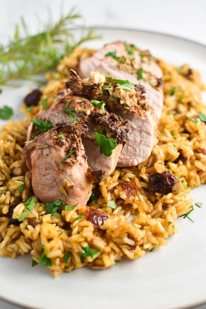 Sliced pork tenderloin served on wild rice with parsley