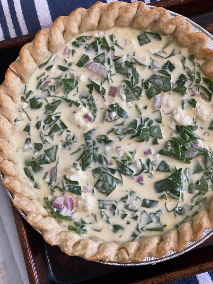 An unbaked quiche florentine on a tray