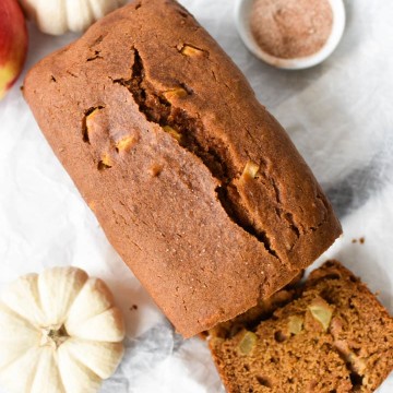 A loaf of pumpkin apple bread that's been sliced with pumpkins and cinnamon sugar