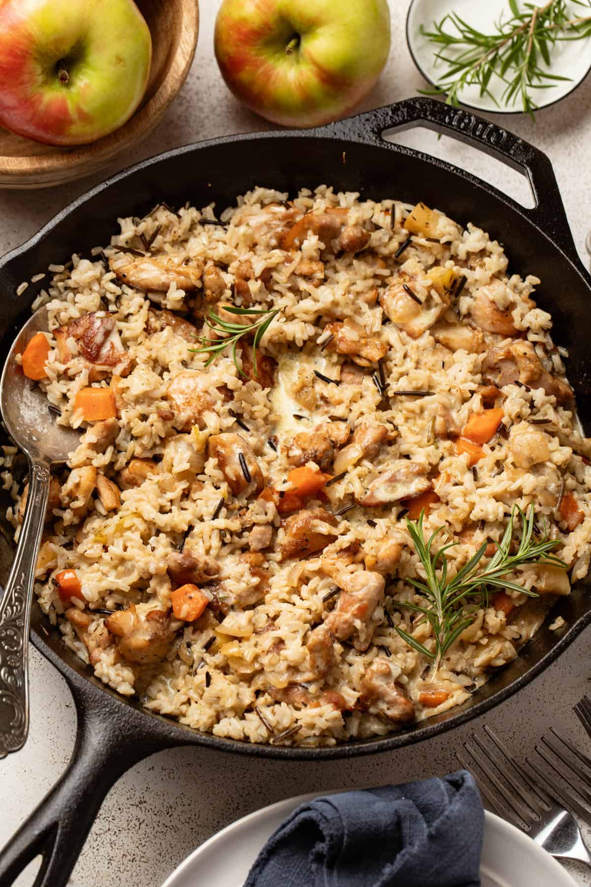 Chicken and wild rice in a cast iron skillet with fresh rosemary on top. 