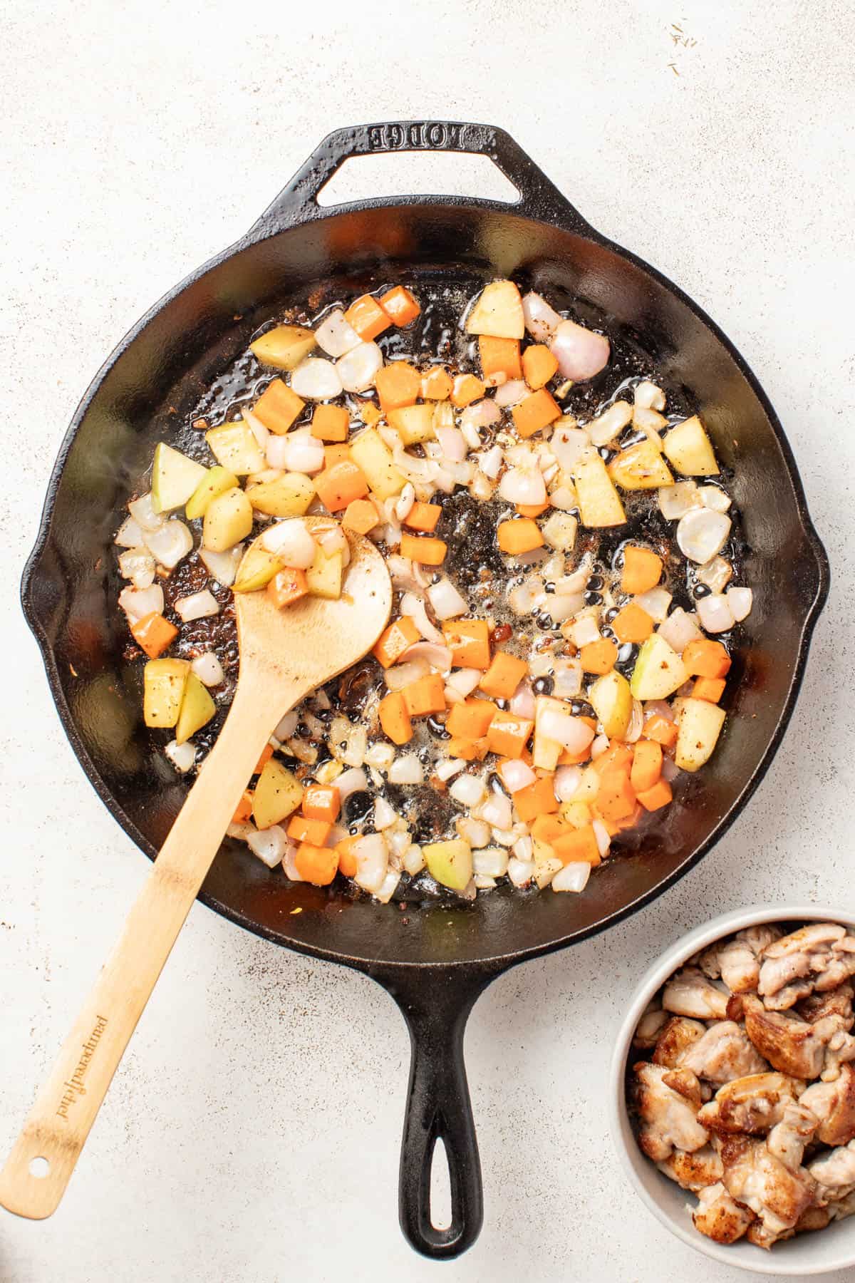 Cooking carrots, apples, and shallots in a cast iron pan.