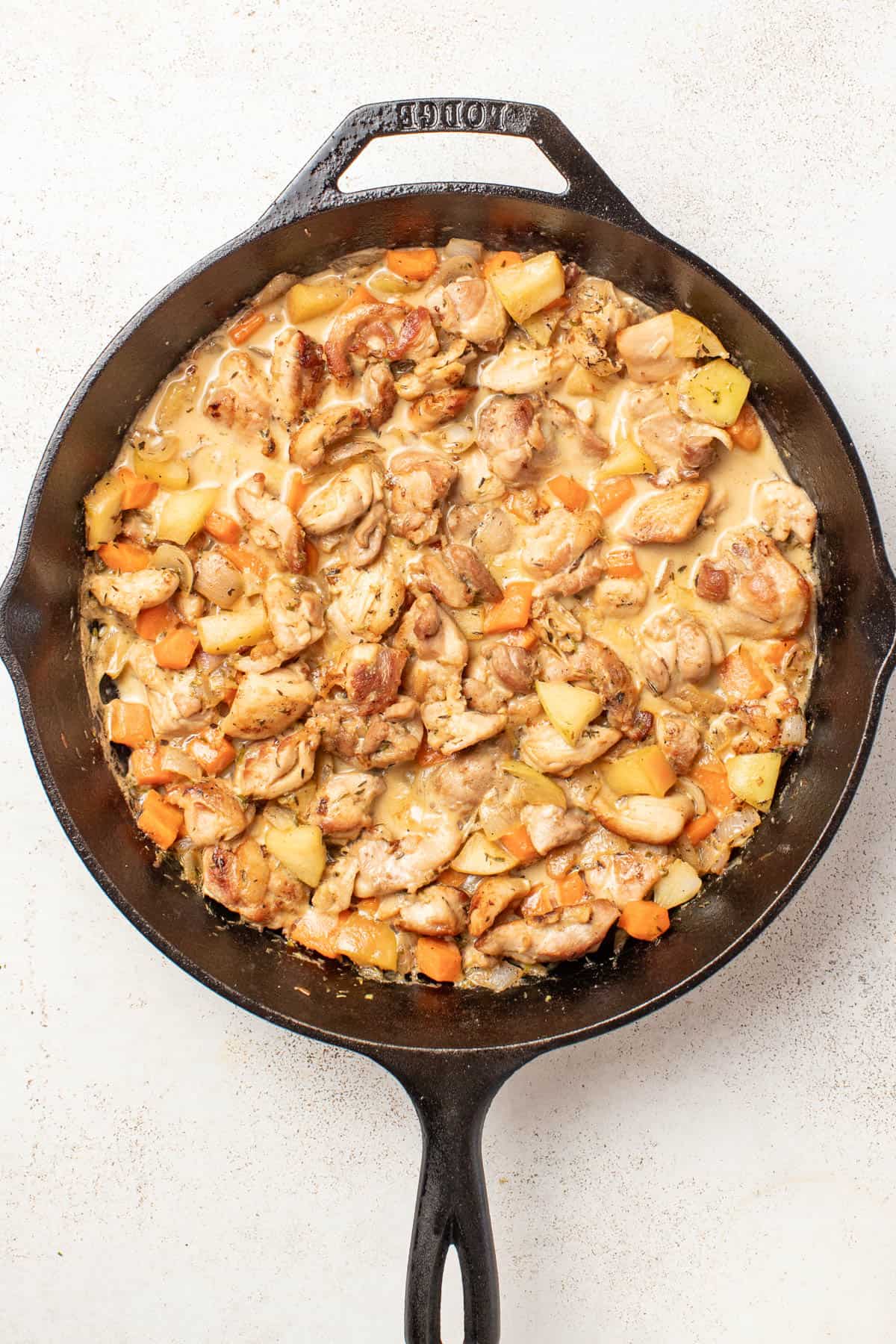 Adding the cooked chicken back into the dijon sauce after being reduced.