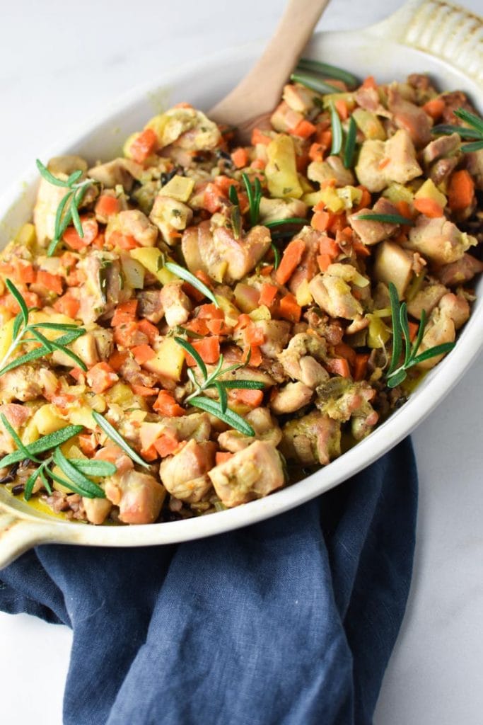 Dijon chicken and wild rice casserole in a white gratin dish with rosemary on top