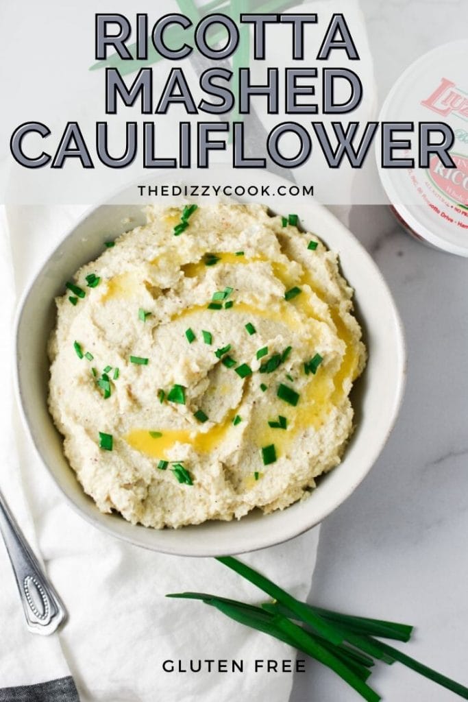 Roasted garlic mashed cauliflower topped with chives in a white bowl with ricotta cheese