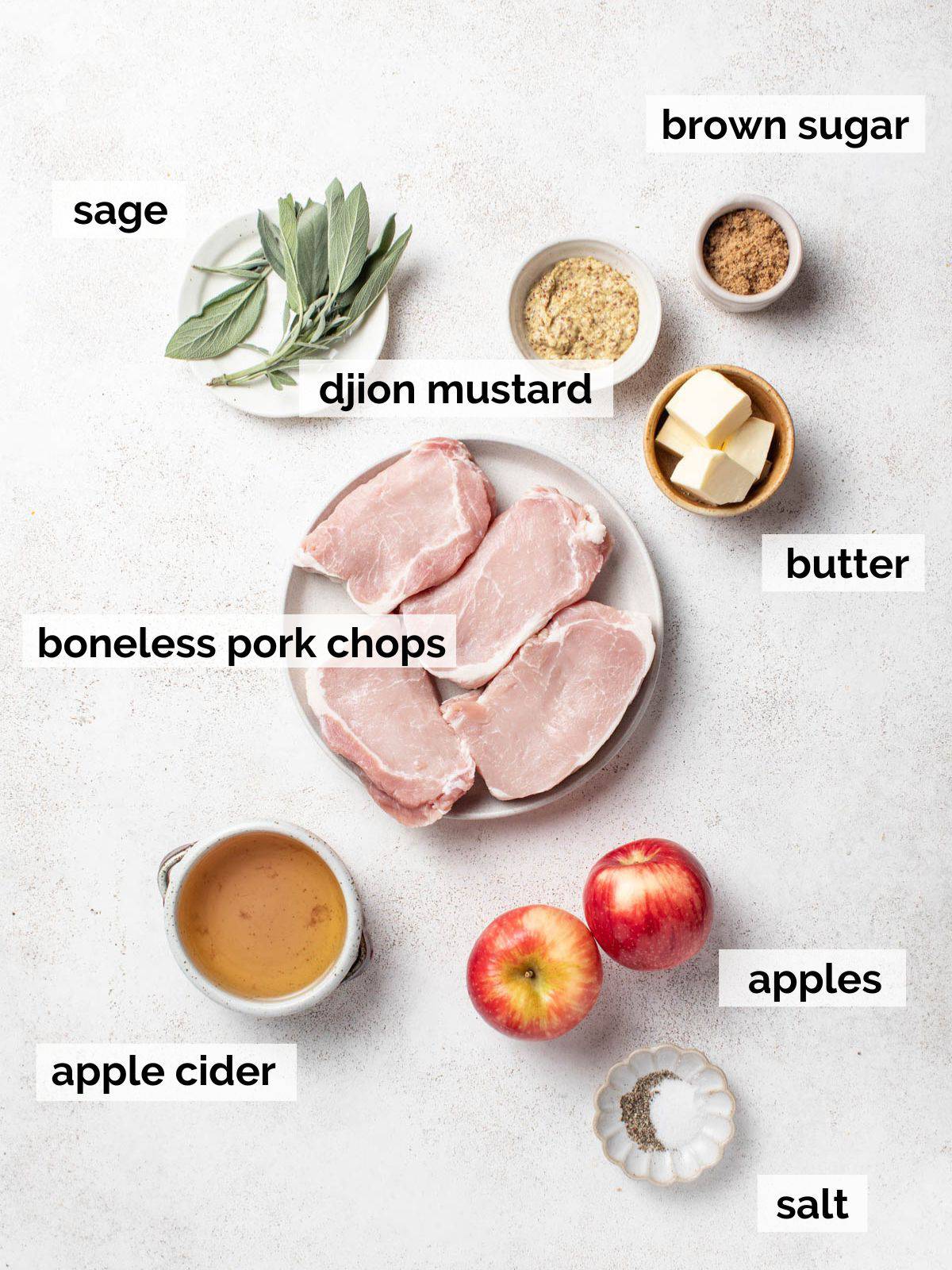 Ingredients for apple cider pork chops with sage on a table. 