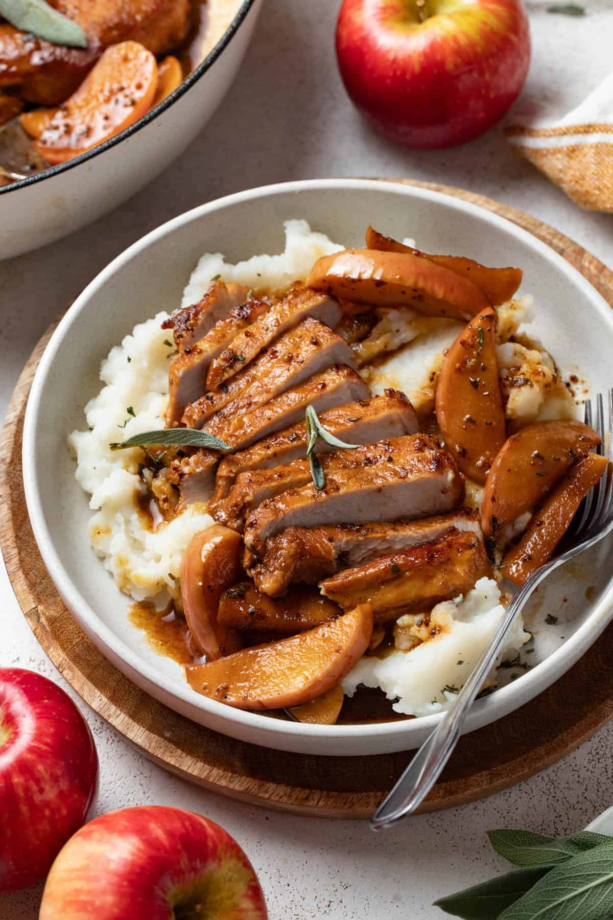 Sliced pork chops with apples and apple cider sauce on top of mashed potatoes.