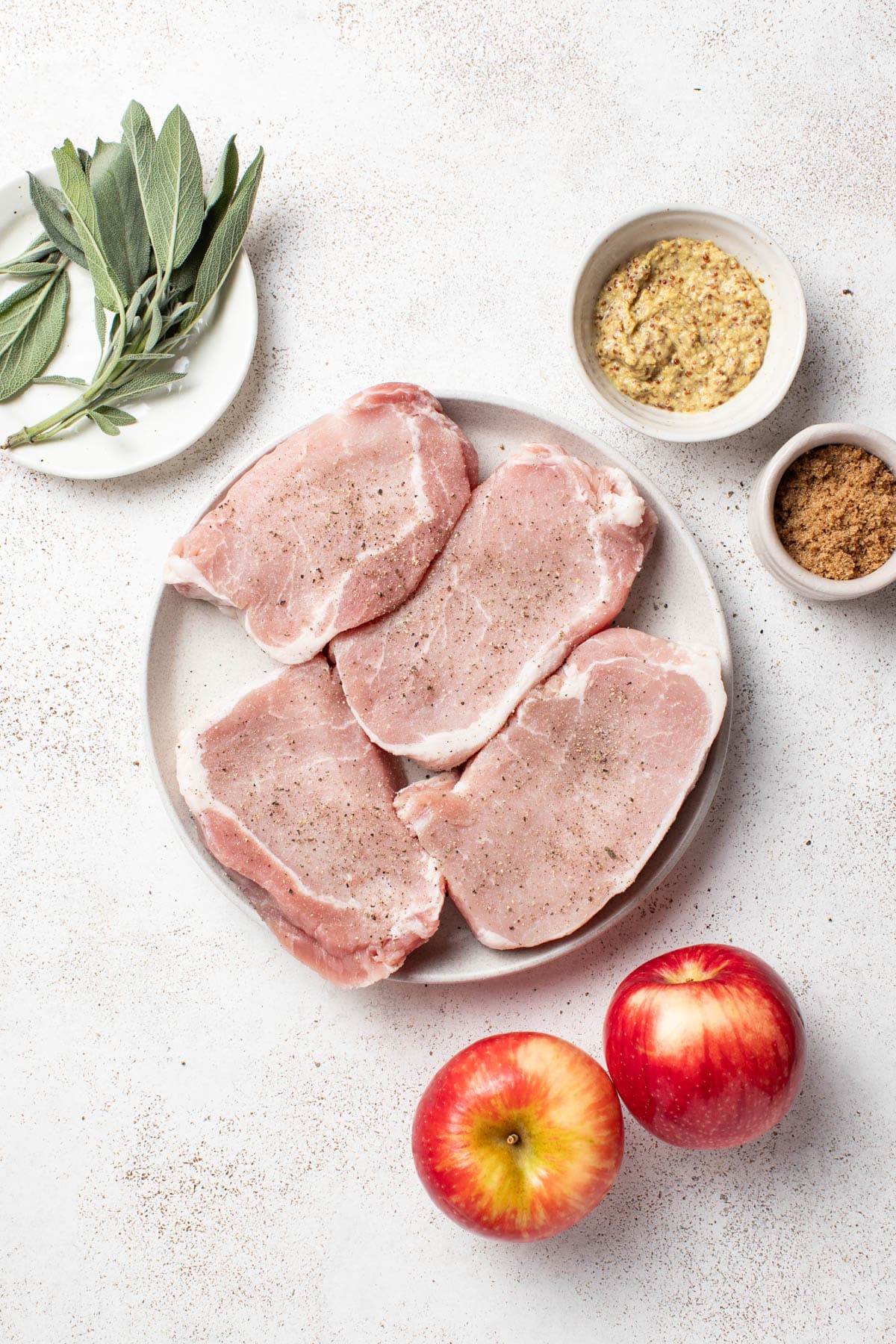 Pork chops sprinkled with salt and pepper on a plate.