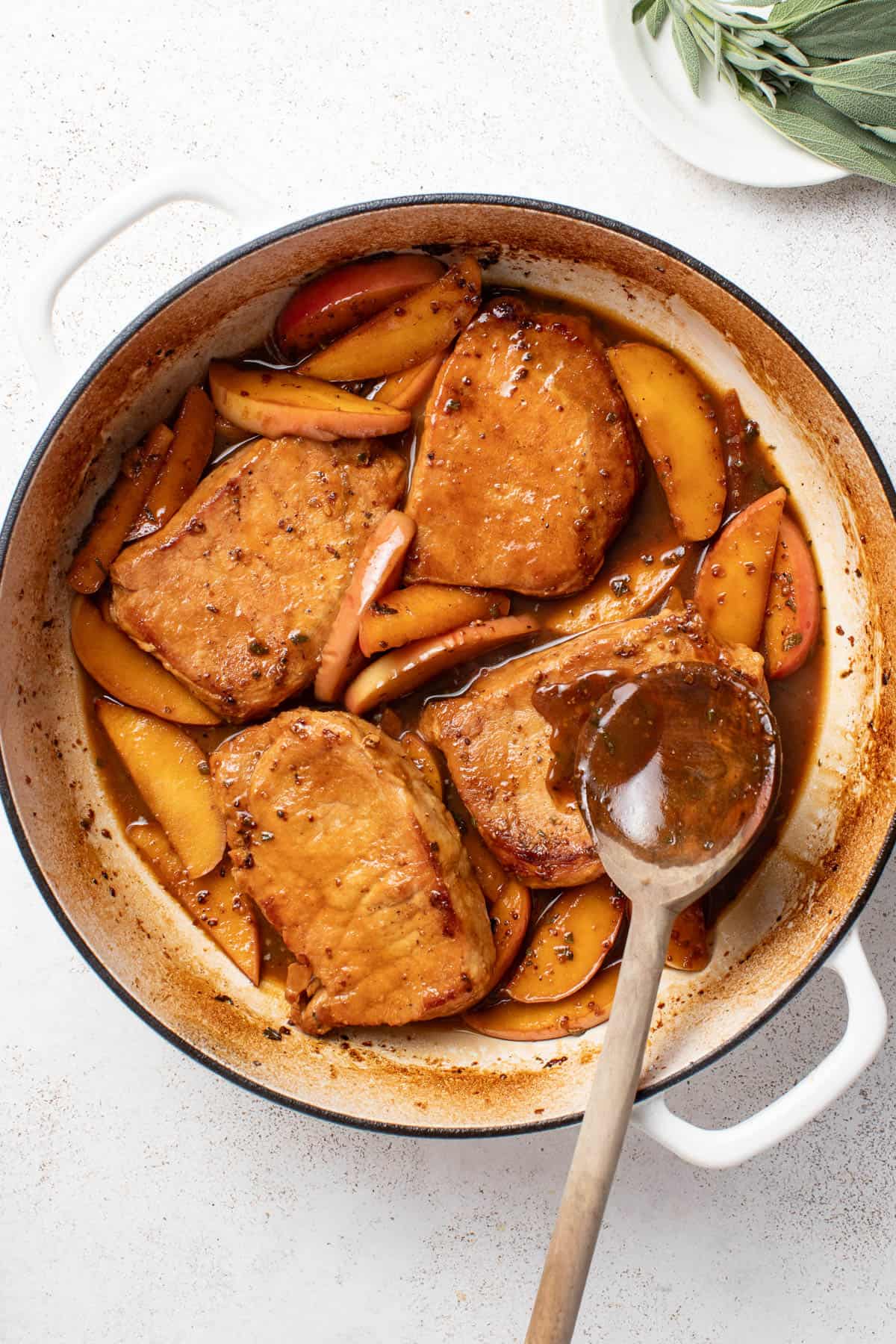Returning cooked pork chops to the dutch oven with apples and apple cider sauce.