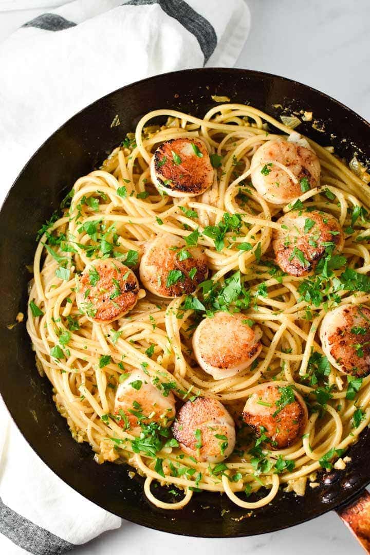 Seared scallops on top of creamy garlic pasta sprinkled with parsley