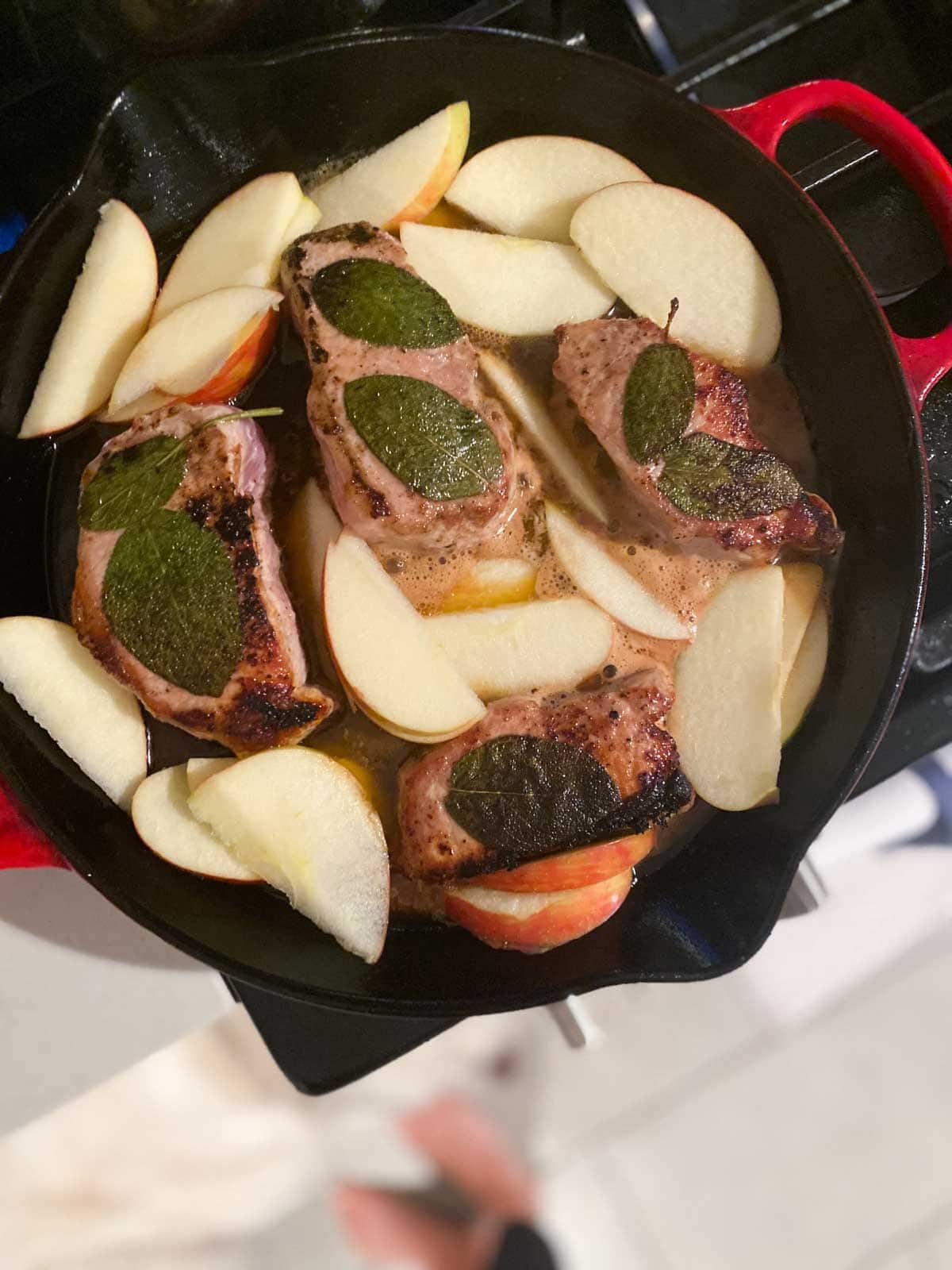 Apple cider added to a pan with pork chops