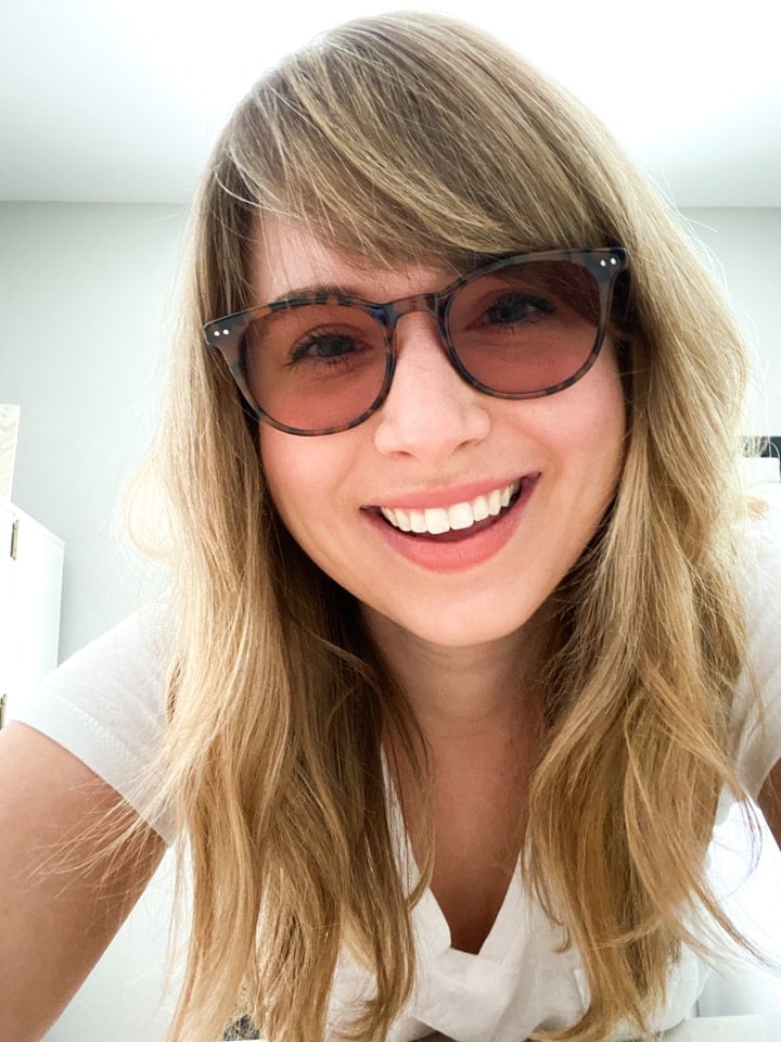 A woman wearing axon optics tutor lenses and smiling.