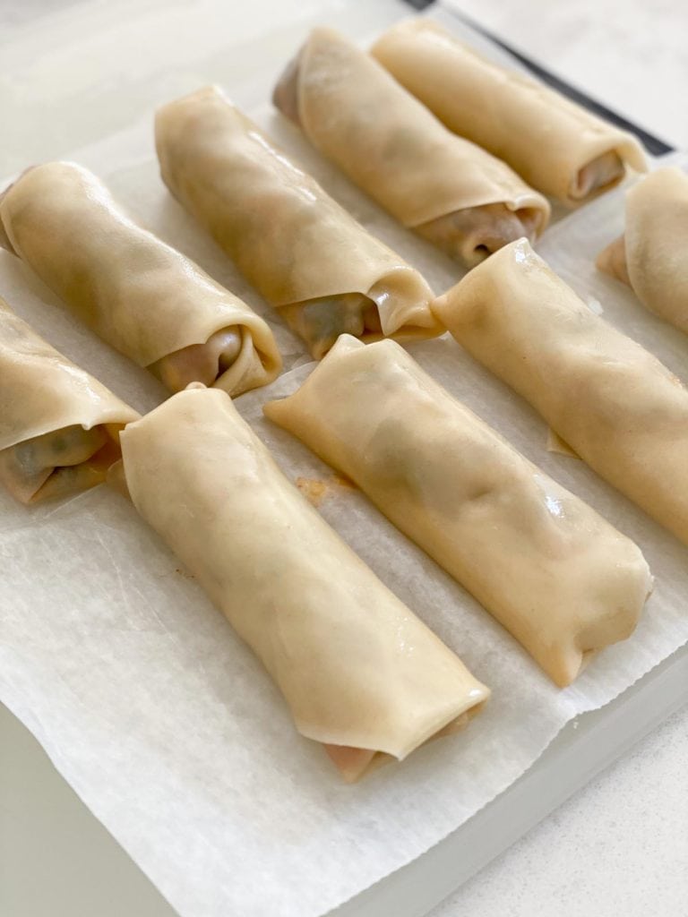 A line of uncooked egg rolls