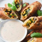 Air fried southwestern egg rolls on a plate with ranch dipping sauce and cilantro