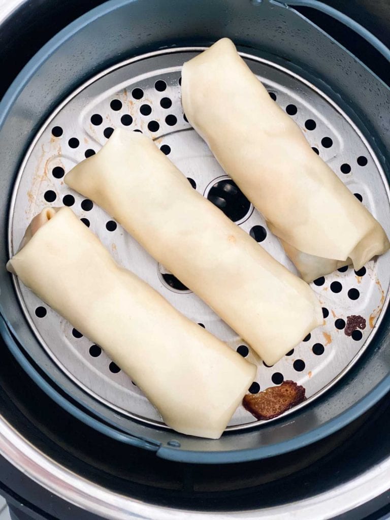 Uncooked egg rolls in an instant pot air fryer basket