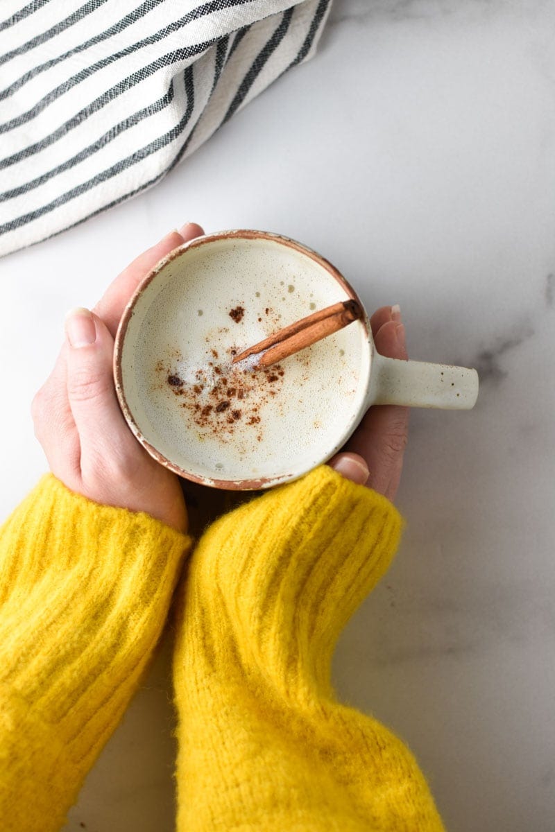 Two hands holding a cup of warm cinnamon milk