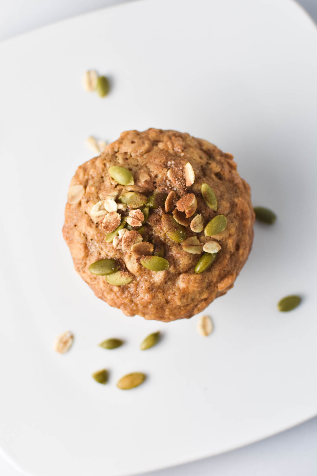 A cinnamon oatmeal muffin topped with sugar on a white table.