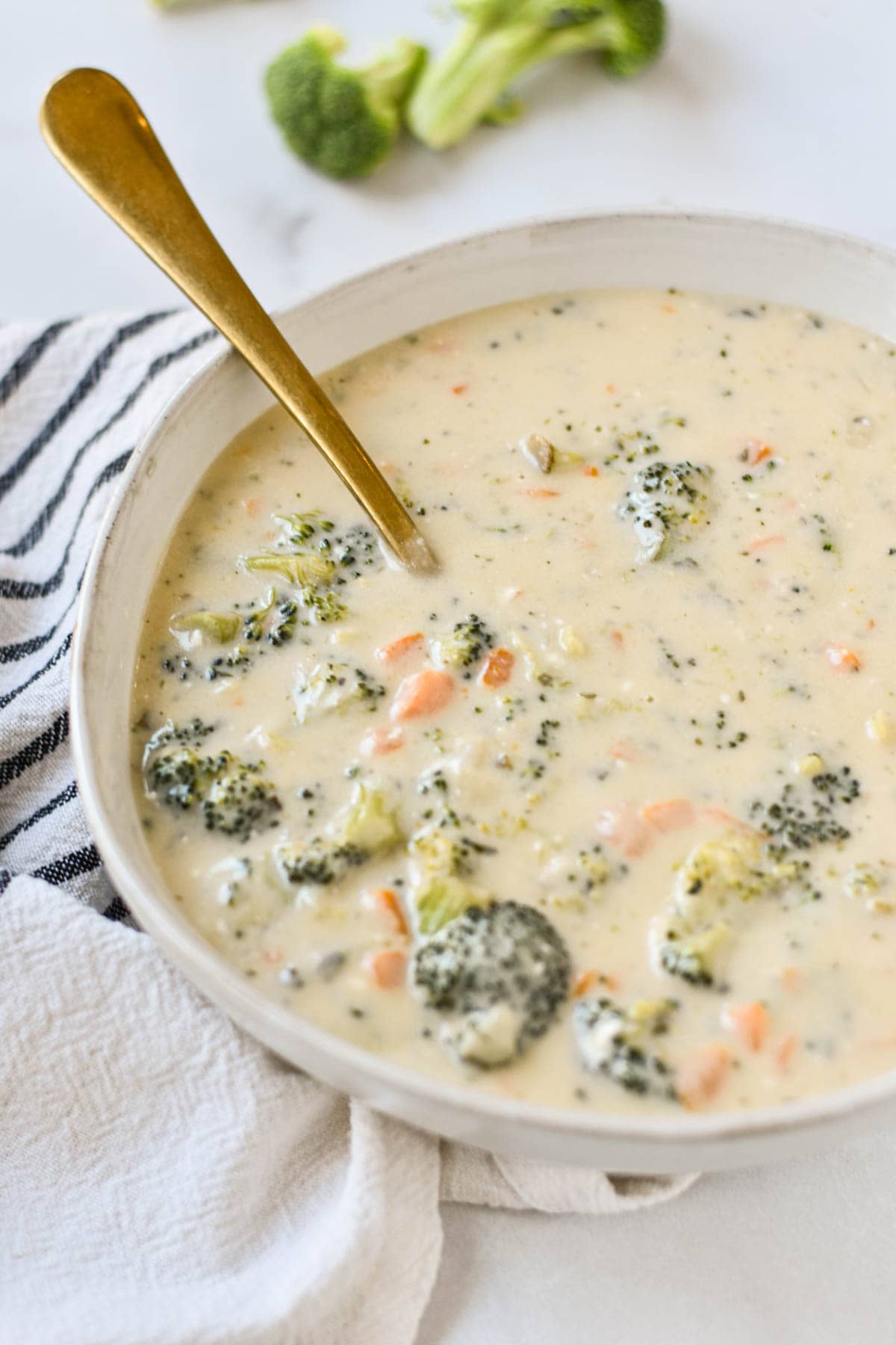 Boursin soup with broccoli in a bowl with a gold spoon.