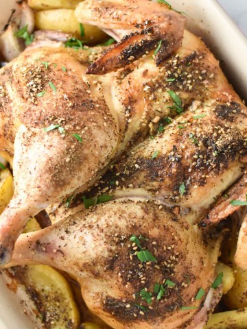 Zaatar roasted chicken on a bed of sumac potatoes and shallots in a roasting dish