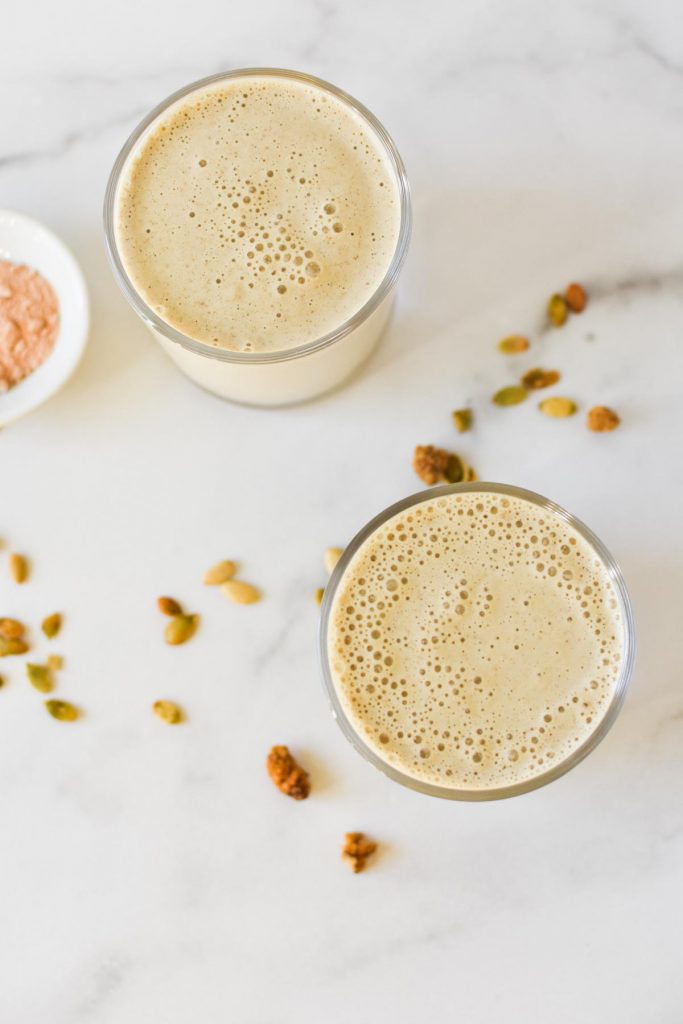 An overhead shot of two smoothies next to lucuma powder, chia seeds, and mulberries