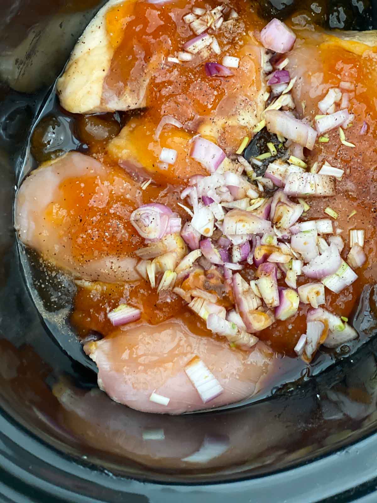 Chicken thighs covered in apricot jam and shallots in a slow cooker