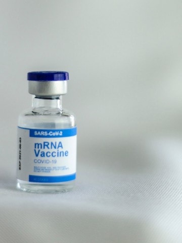 A vial of the COVID 19 vaccine on a white table