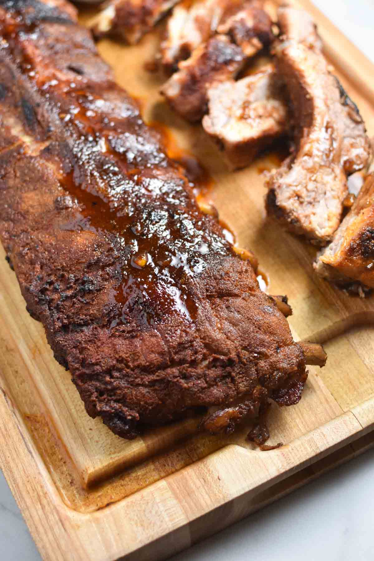 An unsliced rack of ribs with the dry rub and bbq sauce on top