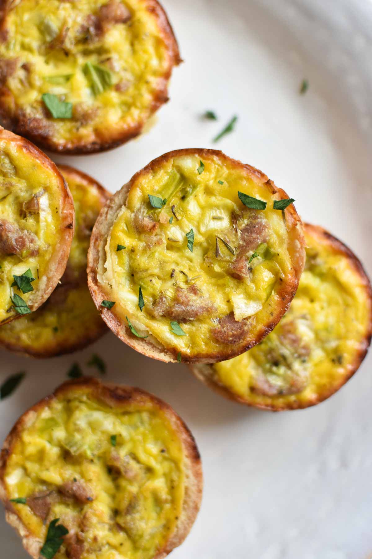 A stacked bunch of muffin tin quiche with parsley sprinkled on top