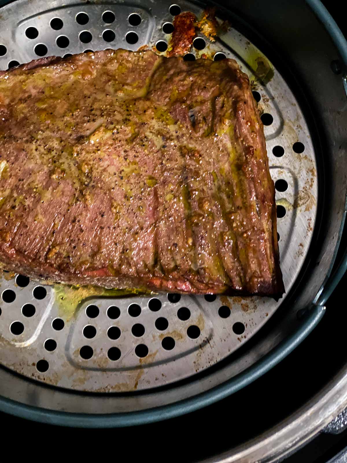 A cooked flank steak in an air fryer.