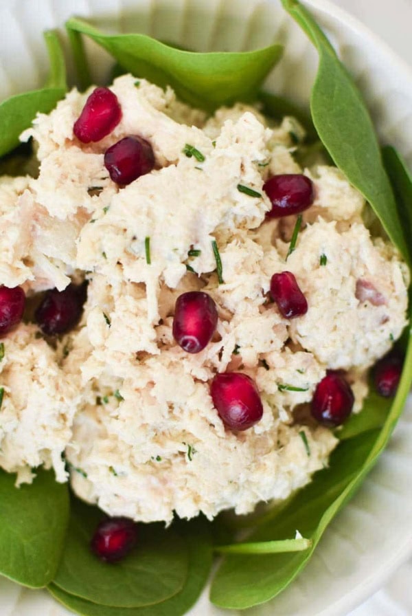Chicken salad on a bed of spinach greens topped with pomegranate seeds