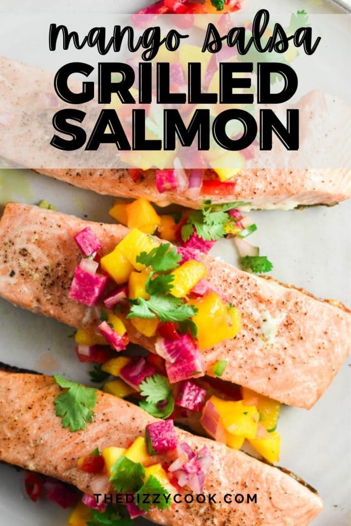 Three filets of grilled salmon topped with a mango salsa on a grey plate.