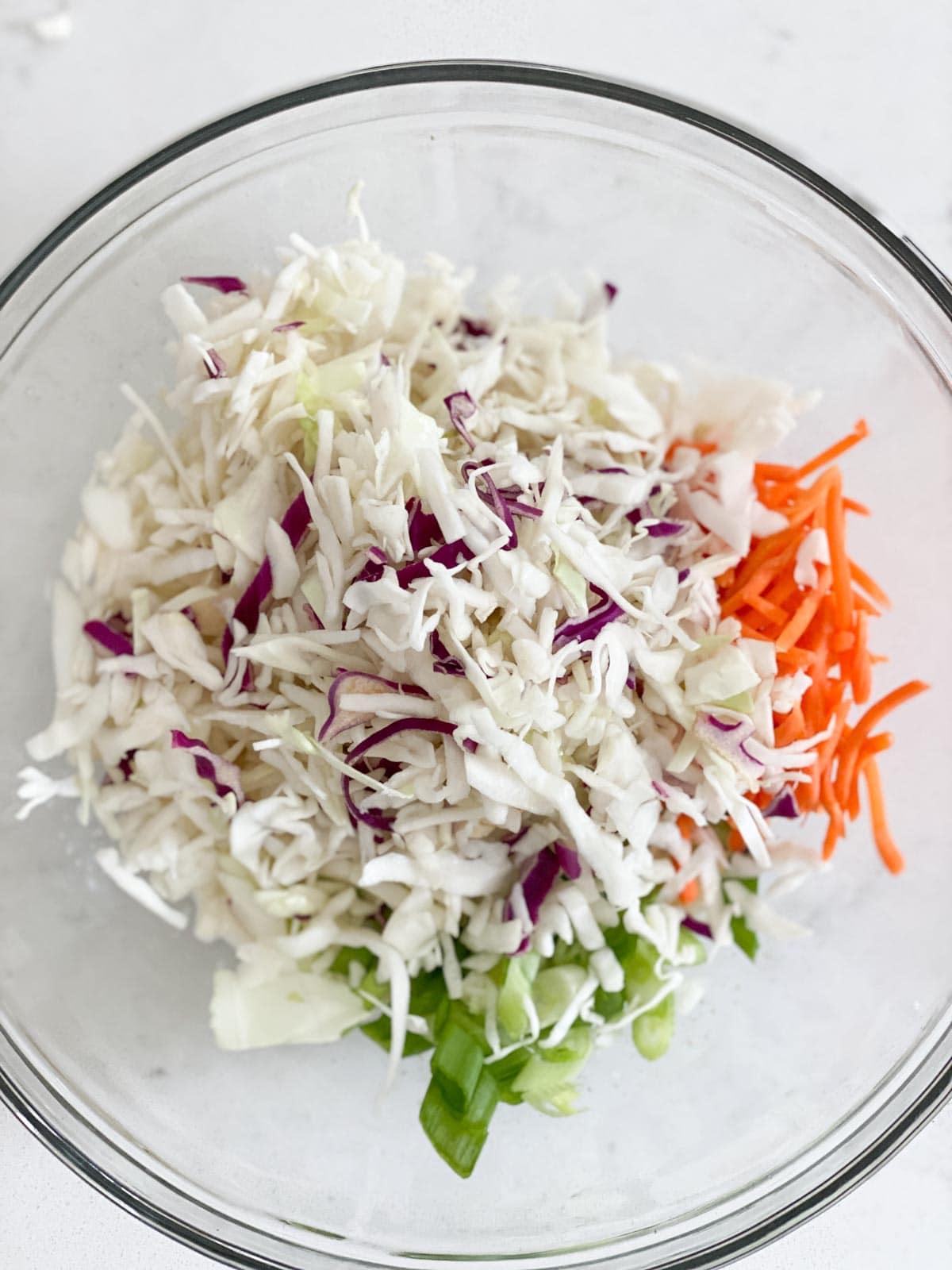 Cabbage, carrots, and green onion added to a coleslaw dressing mixture.