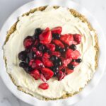 Fresh summer berries on top of a vanilla ice cream pie with an oat crust on a white marble table