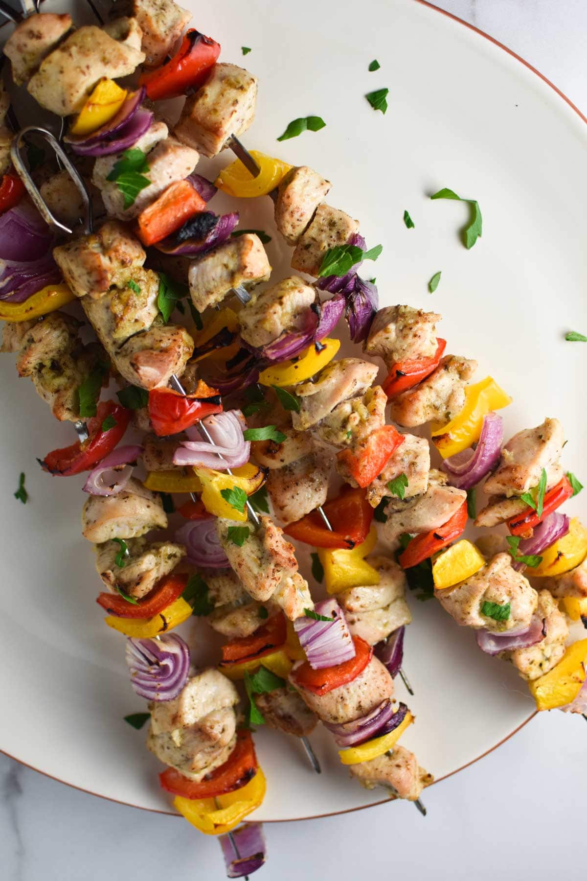 A plate of oven baked chicken kabobs stacked on top of each other.