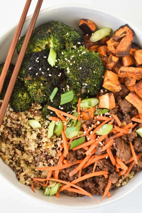 A ground beef stir fry in a white bowl with chopsticks on the side