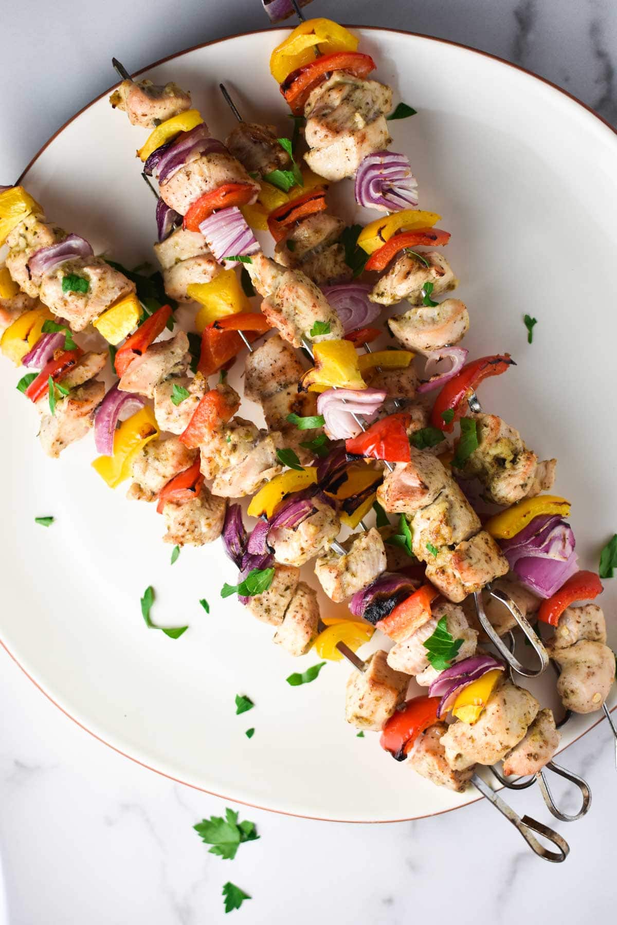 Chicken, peppers, shallots on a metal skewer.