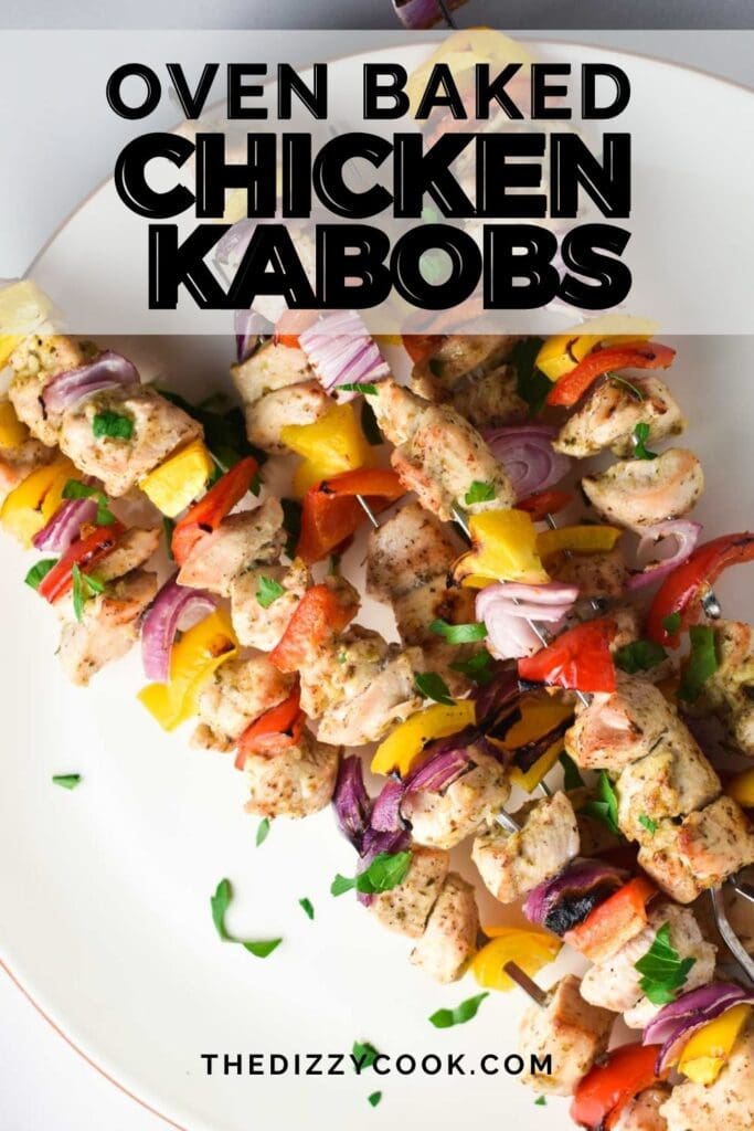 Baked chicken kabobs laid out diagonally on a plate and topped with parsley
