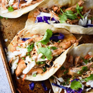 An up close shot of a chicken tinga taco with sauce dripping out