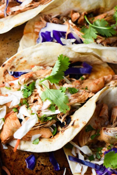 An up close shot of a chicken tinga taco with sauce dripping out