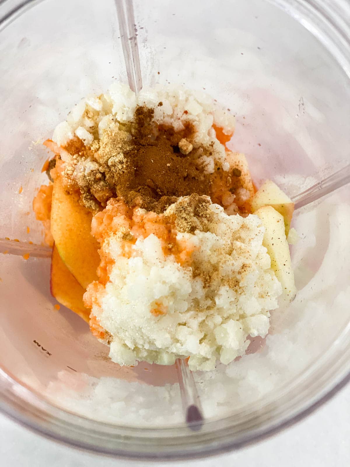 Carrots, cauliflower, spices, and apples in a blender.